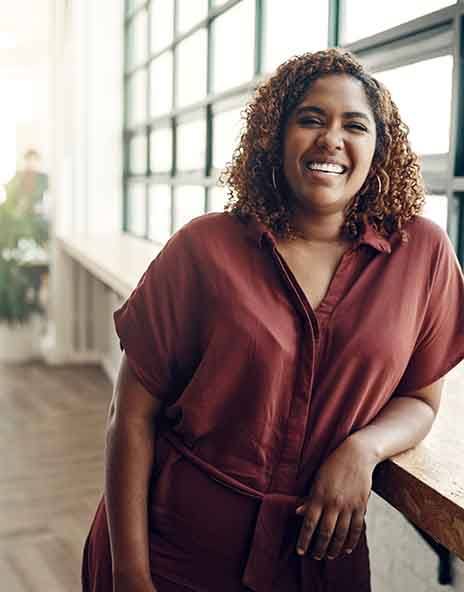 a smiling woman resting against a railing