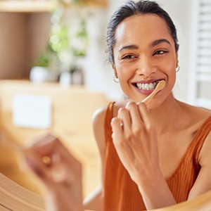 Woman brushing her teeth in the mirror