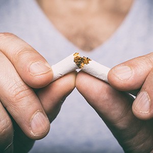 Person breaking a cigarette in half