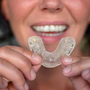 Woman holding a mouthguard to protect her teeth