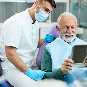 Man looking at his smile while at the dentist’s office