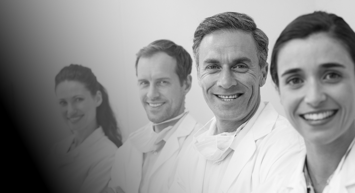 Four smiling dentists standing in a row
